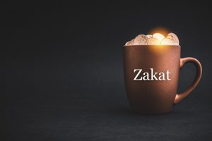 ZAKAT or ISLAMIC TAX text with Coins in cups on black background.